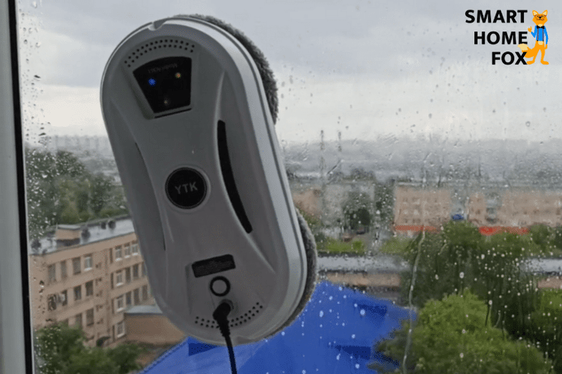 На стекле виден круглый робот для мойки окон.